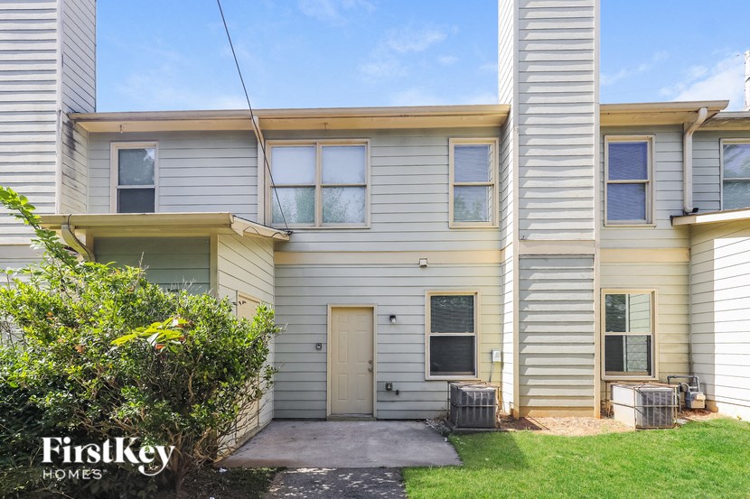 the front of a white house with a sidewalk and grass