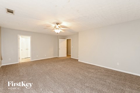 a spacious living room with carpet and a ceiling fan