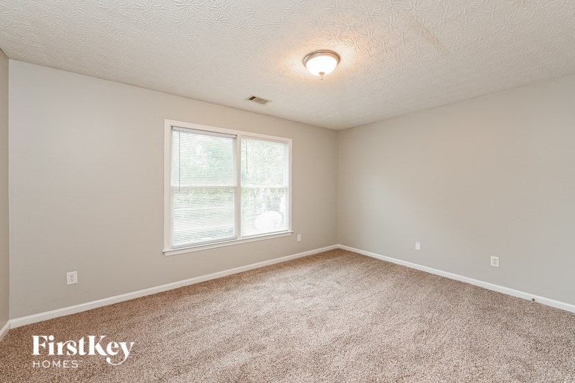 the spacious bedroom with carpeting and a large window