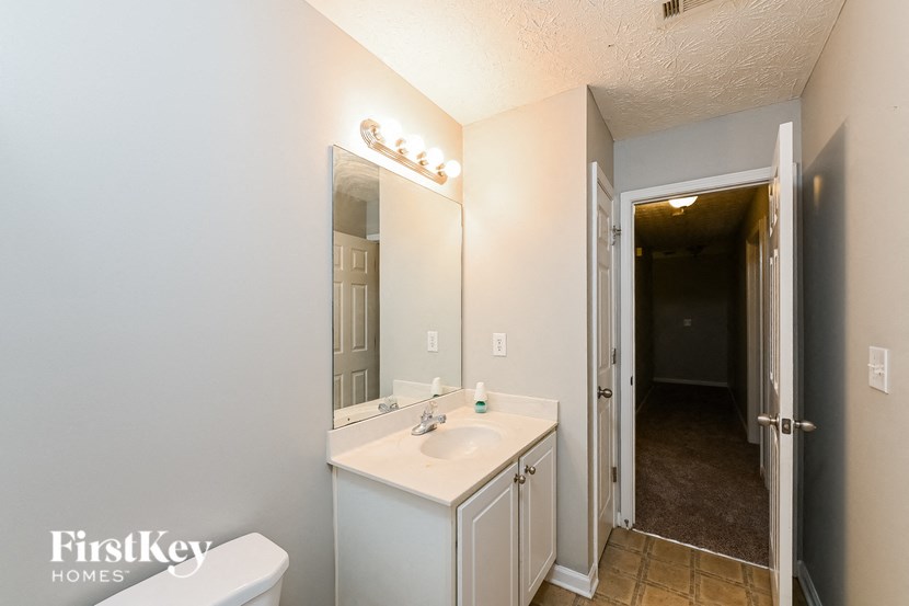 a bathroom with a sink and a mirror and a door to a hallway