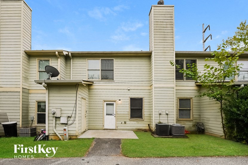 the front of a yellow house with a lawn and a driveway