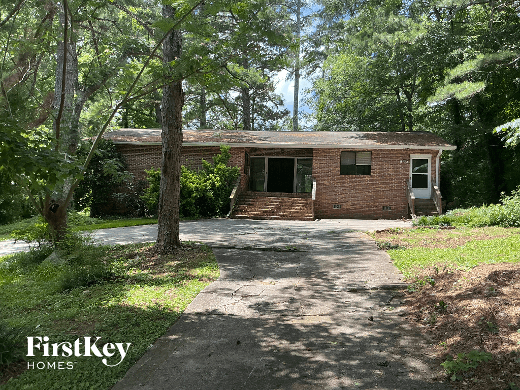 A house with a driveway and trees in front of it.