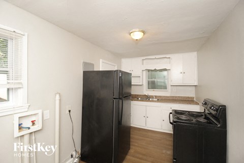 a kitchen with white cabinets and a black refrigerator