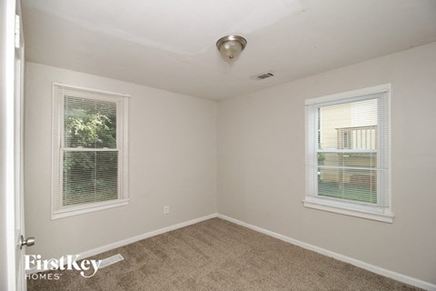 a bedroom with carpet and two windows