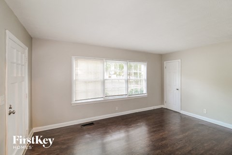 A room with wooden floors and a window with blinds.