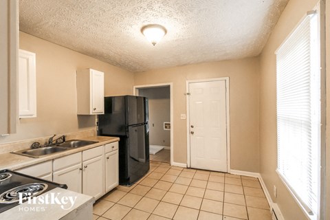 A kitchen with a black fridge and white cabinets.