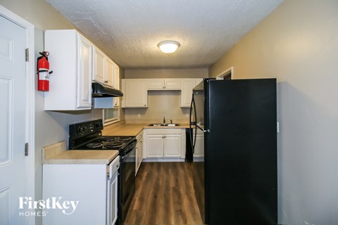 A kitchen with a black refrigerator and white cabinets.