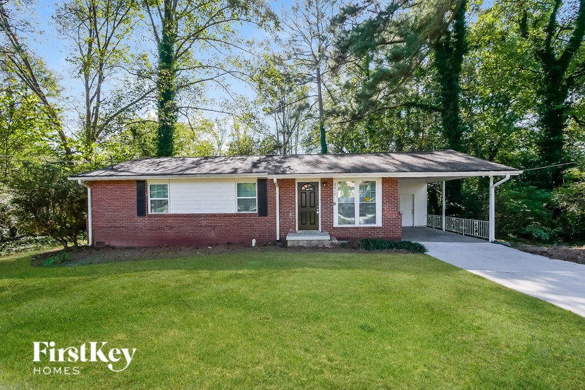 a small brick house with a front yard and a driveway