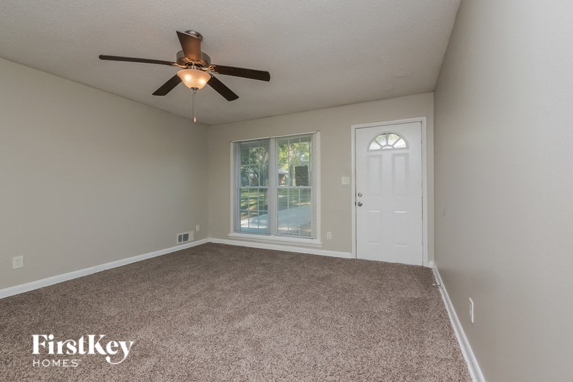 an empty living room with a ceiling fan and a window