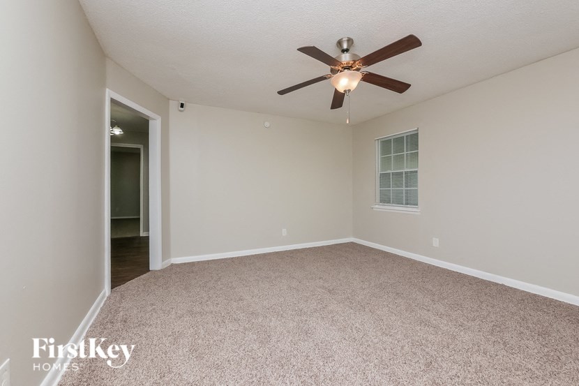a spacious living room with carpet and a ceiling fan