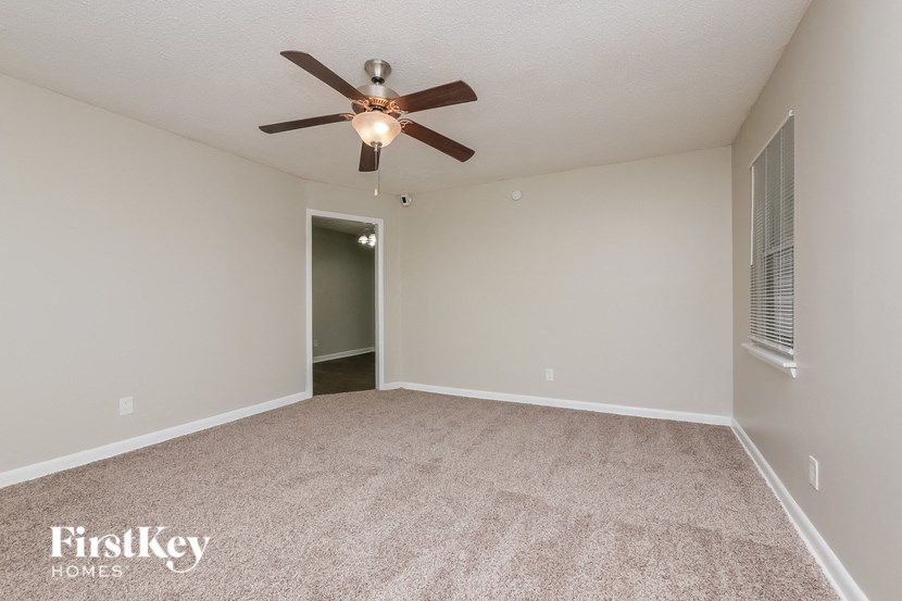 the spacious living room with ceiling fan and carpeting