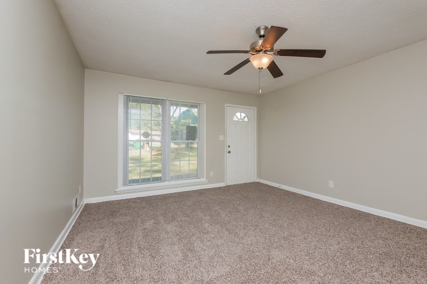 an empty living room with a ceiling fan and a window