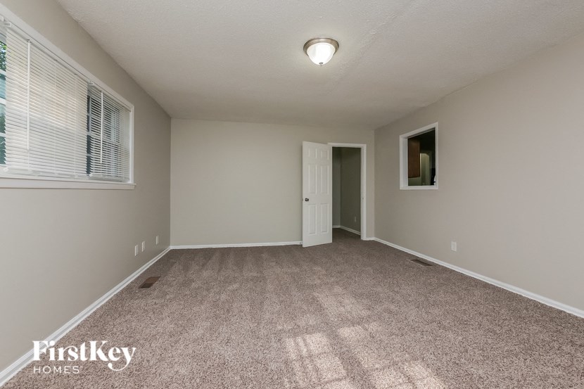 a spacious living room with carpeted flooring and a window