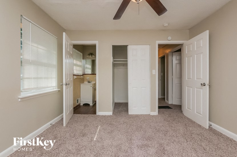 a bedroom with a ceiling fan and a closet and a door to a bathroom