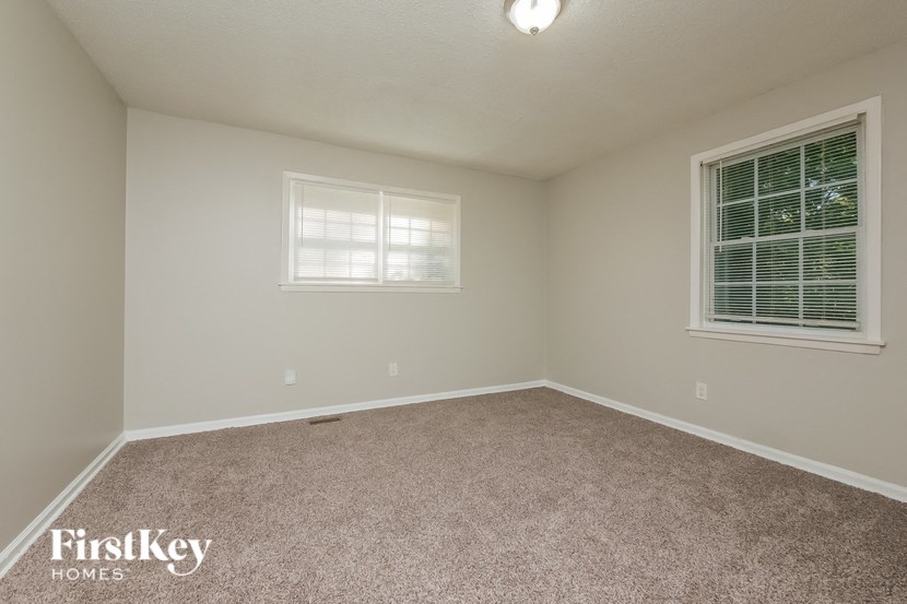 a bedroom with a carpeted floor and two windows