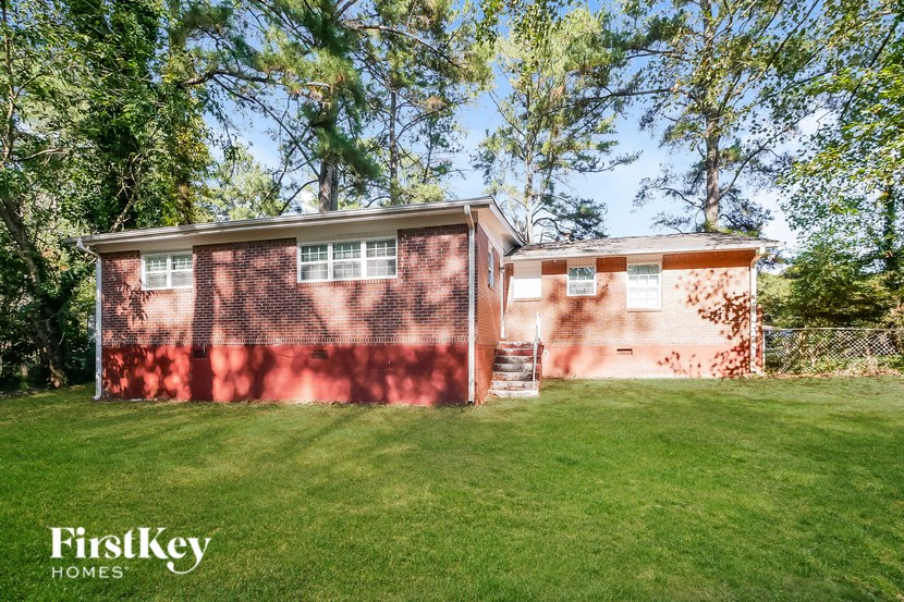 a red brick house with a green lawn and trees