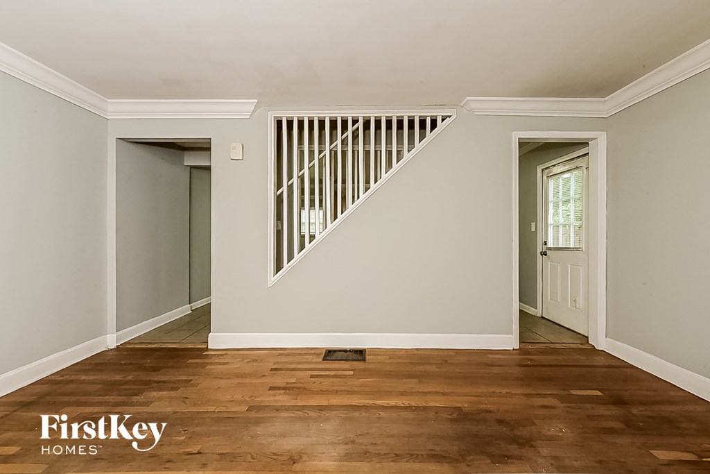 a renovated living room with white walls and wooden floors and a white staircase