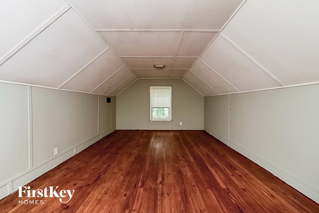 a room with wood floors and white walls and a window