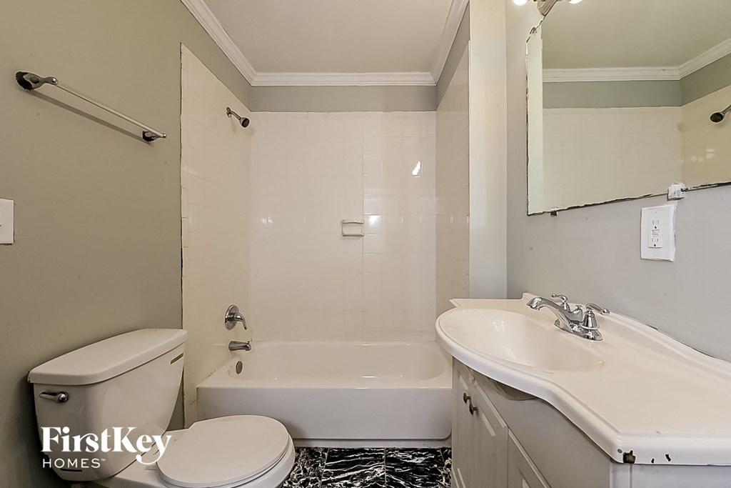 a white bathroom with a toilet sink and tub and a mirror