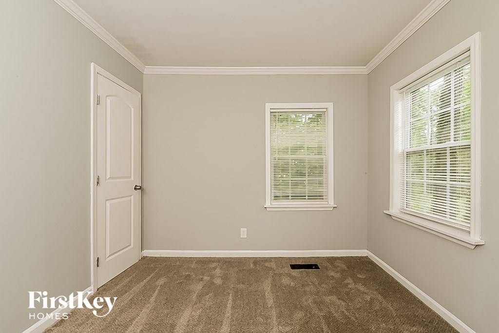 a bedroom with carpet and two windows and a door