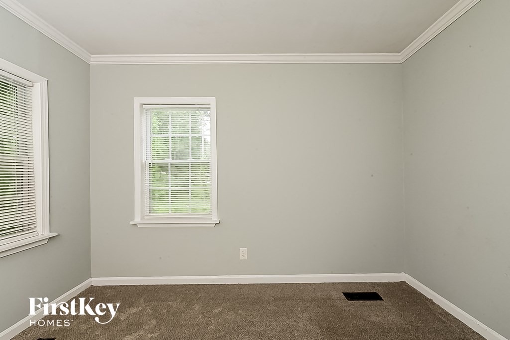 a empty room with carpet and two windows