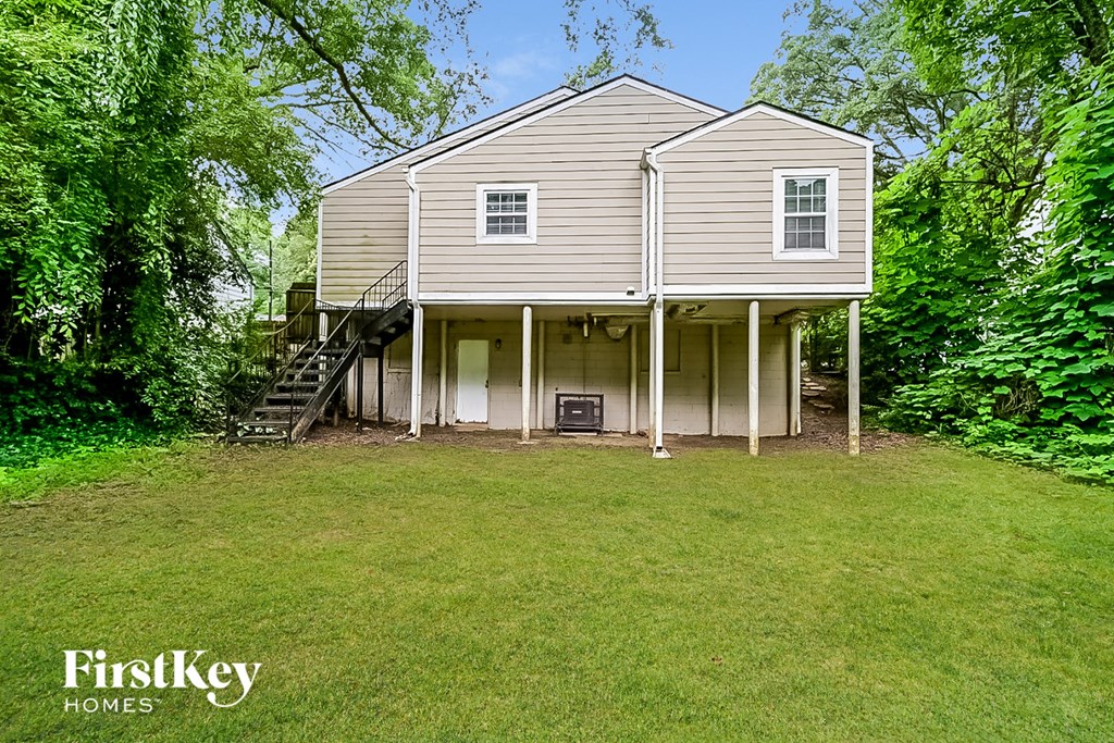 the back of a house with a lawn and trees