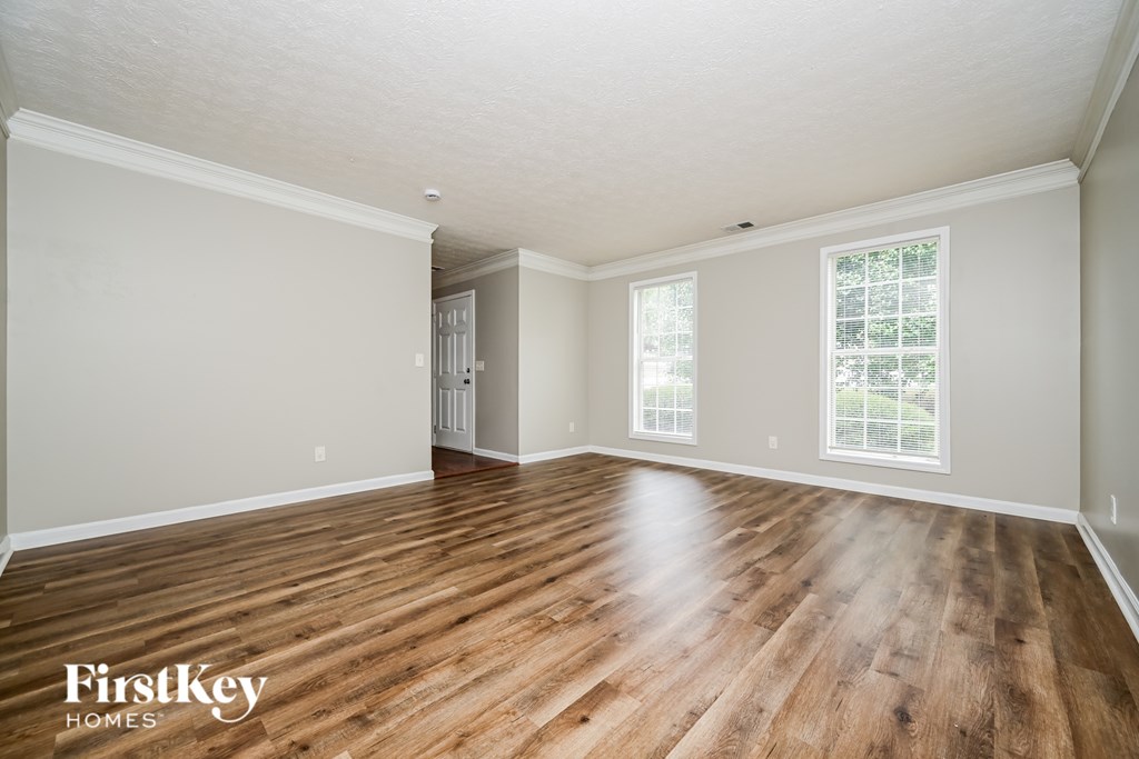 A room with wooden floors and white walls, with a window on the right side.