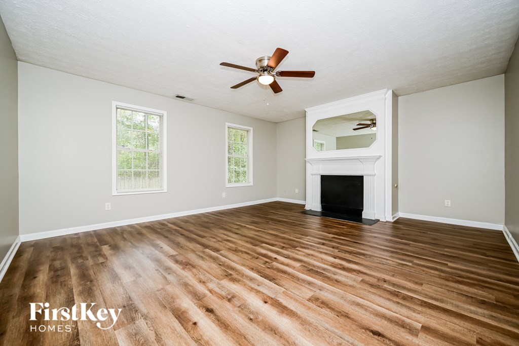 A spacious room with wooden floors and a fireplace.