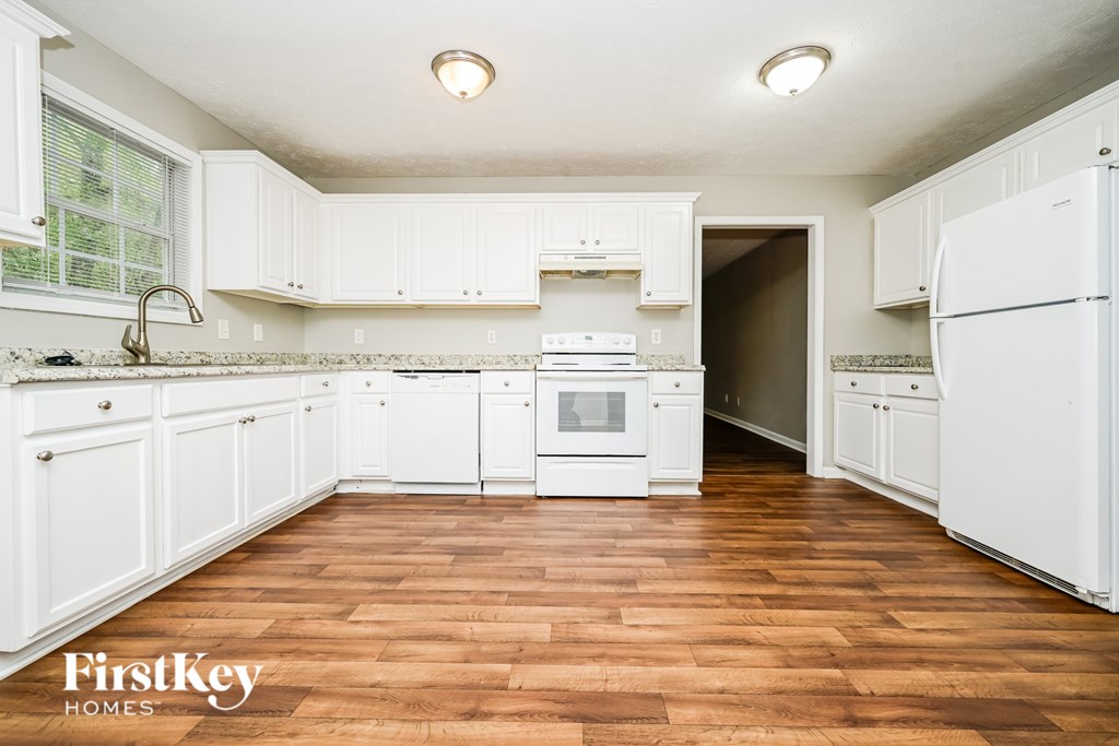 A kitchen with white cabinets and a wooden floor.