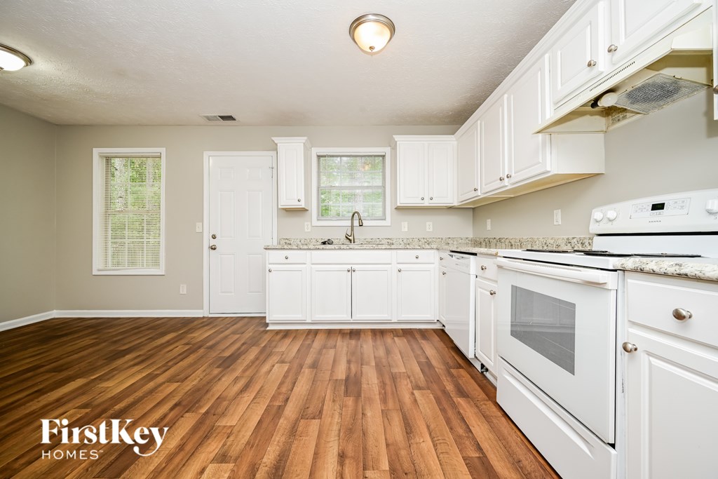 A kitchen with wooden floors and white cabinets.