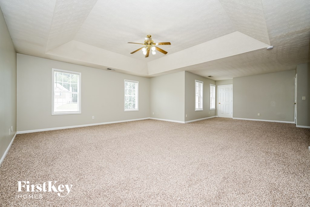 A spacious room with a ceiling fan and carpeted floor.