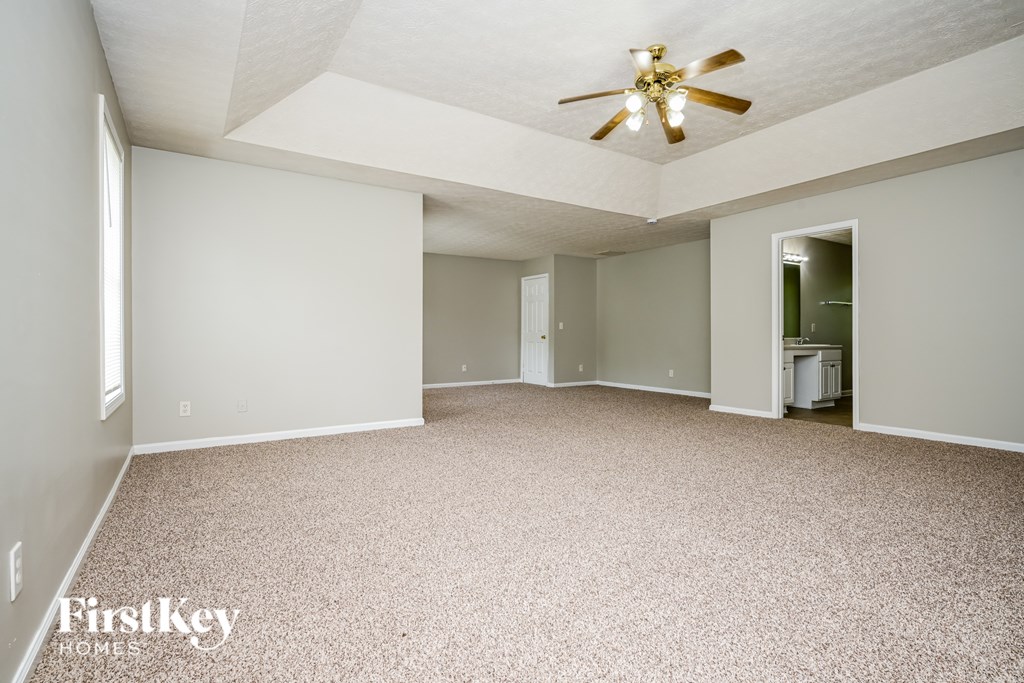 A spacious room with a ceiling fan and carpeted floor.