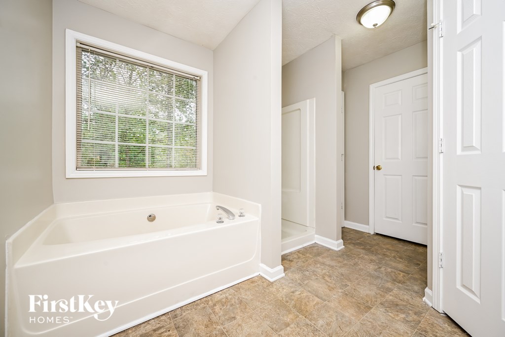 A white bathroom with a tub and a window.