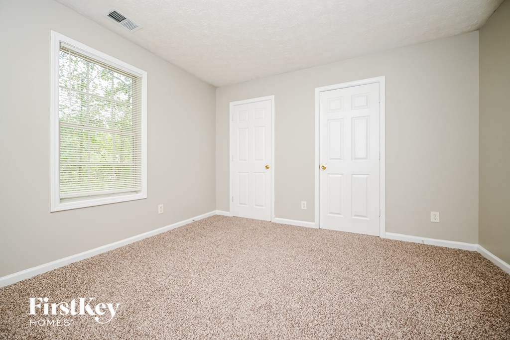 A room with a carpeted floor and two white doors.