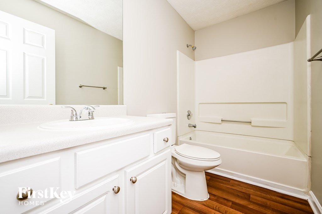 A white bathroom with a toilet, sink, and bathtub.