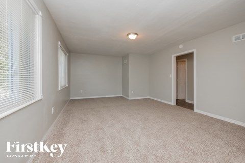 a spacious living room with white carpet and a large window