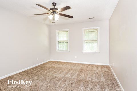 the spacious living room with ceiling fan and carpet