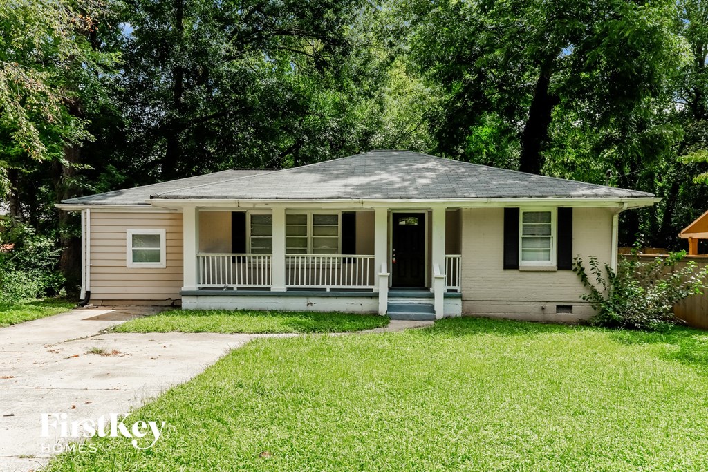 a small cream colored house with a porch and trees