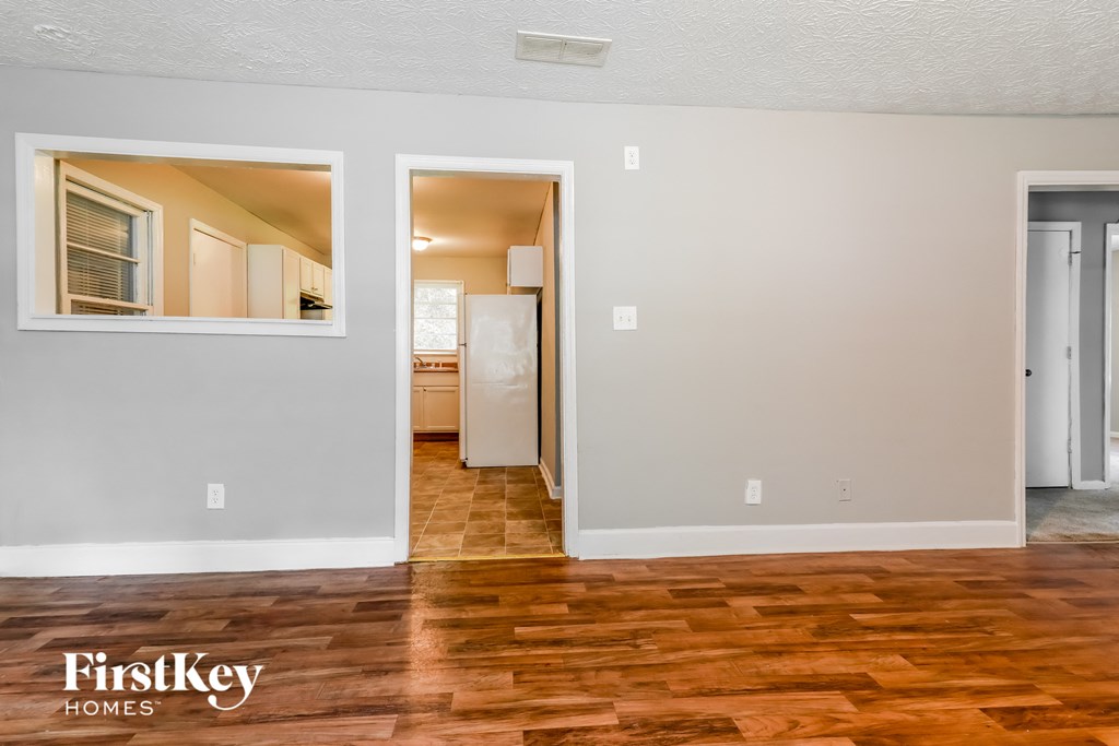 the living room and dining room with wood flooring and a door to the kitchen