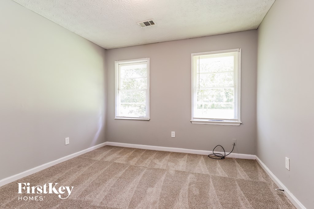 a empty room with two windows and a carpeted floor