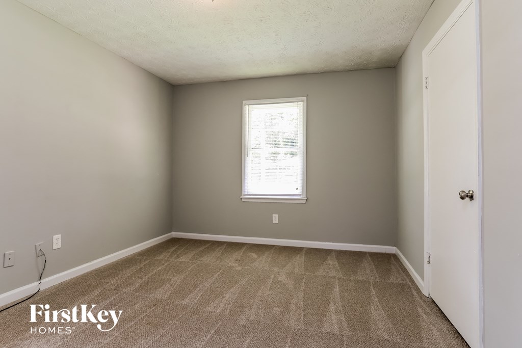 the living room of an empty house with carpet and a window