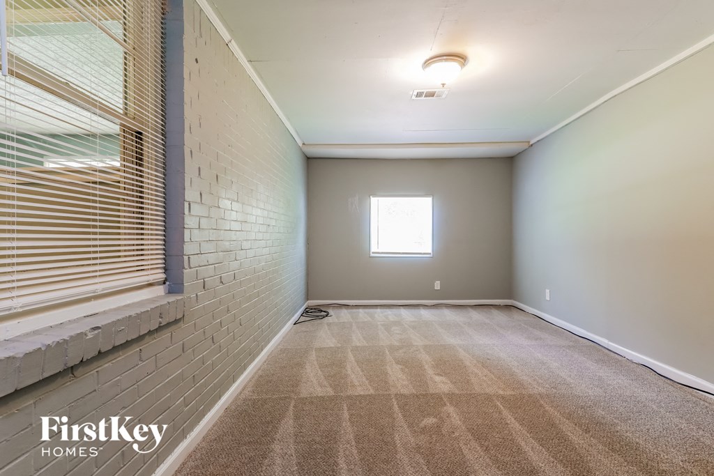 a empty room with a window and a white brick wall