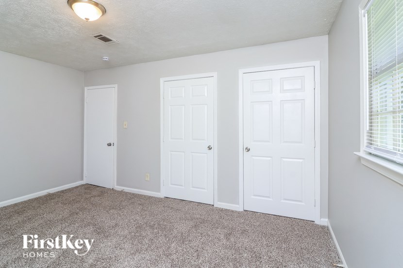 A room with three white doors and a carpeted floor.