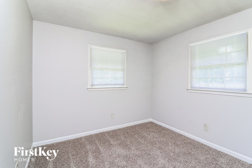 A room with two windows and a carpeted floor.