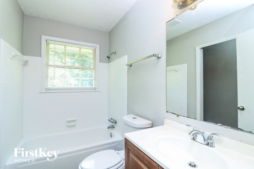 A white bathroom with a toilet, sink, and a window.