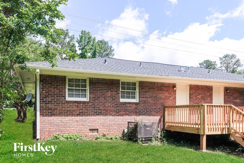 A brick house with a porch and a tree in front.