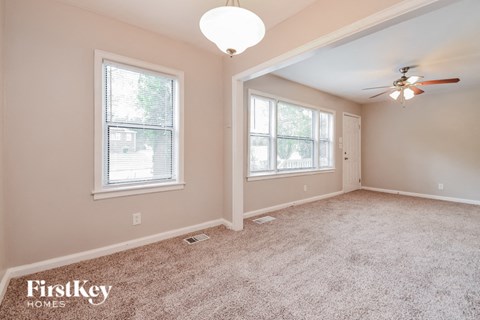 an empty room with a ceiling fan and two windows