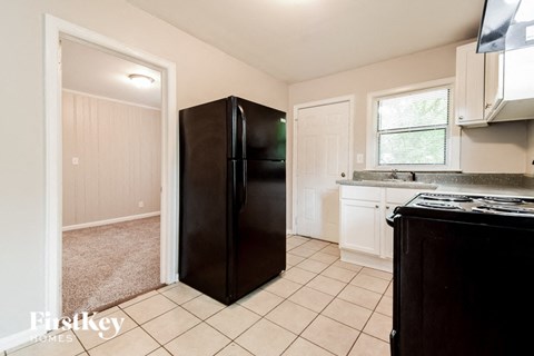 a kitchen with a black refrigerator and white cabinets