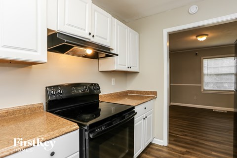 A kitchen with a black stove top oven and white cabinets.