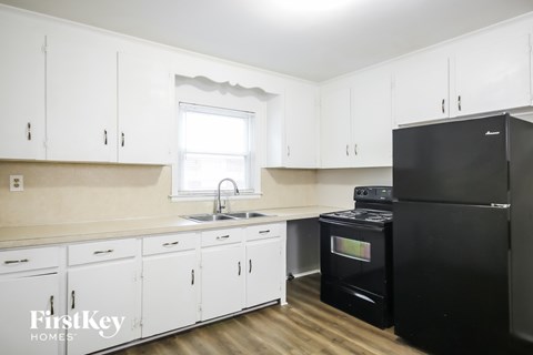 A kitchen with white cabinets and a black fridge.